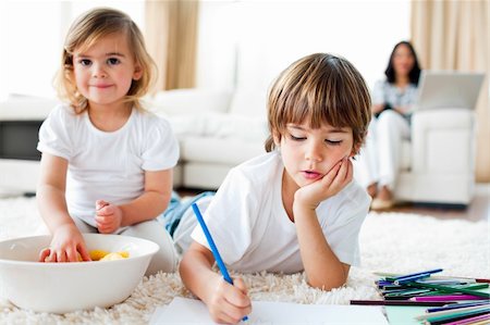 Serious little boy drawing and his sister eating chips lying on the floor Stock Photo - Budget Royalty-Free & Subscription, Code: 400-04198769