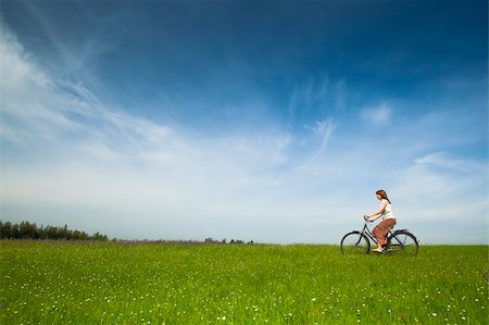 simsearch:400-04201795,k - Happy young woman on a green meadow riding a bicycle Fotografie stock - Microstock e Abbonamento, Codice: 400-04198834
