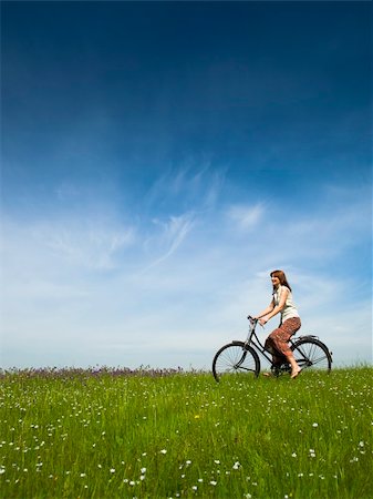 simsearch:400-04201795,k - Happy young woman on a green meadow riding a bicycle Fotografie stock - Microstock e Abbonamento, Codice: 400-04198836