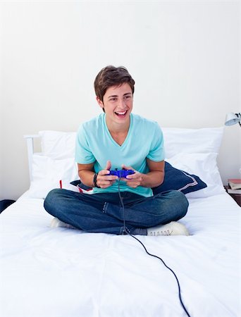 Excited teenager playing video games on his bed Stock Photo - Budget Royalty-Free & Subscription, Code: 400-04199095