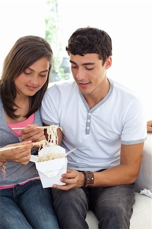 Couple of teenagers eating pasta at home on the sofa Stock Photo - Budget Royalty-Free & Subscription, Code: 400-04199155