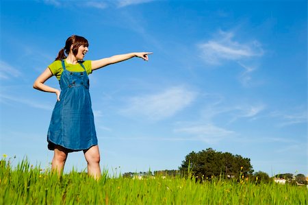 simsearch:400-04201795,k - Portrait of a beautiful woman on a green meadow pointing to somewhere Fotografie stock - Microstock e Abbonamento, Codice: 400-04190669