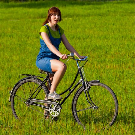 simsearch:400-04201795,k - Happy young woman on a green meadow riding a bicycle Fotografie stock - Microstock e Abbonamento, Codice: 400-04190674