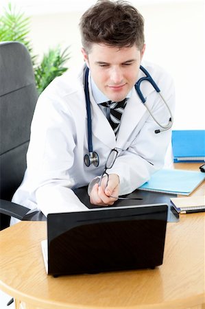 simsearch:400-04191693,k - Assertive male doctor using a laptop sitting at his desk in a practice Stock Photo - Budget Royalty-Free & Subscription, Code: 400-04191696
