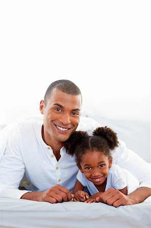 simsearch:400-04192370,k - Attentive father and his daughter lying on a bed smiling at the camera Stock Photo - Budget Royalty-Free & Subscription, Code: 400-04192366