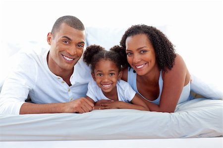 Affectionate parents and their daughter lying on a bed smiling at the camera Stock Photo - Budget Royalty-Free & Subscription, Code: 400-04192368
