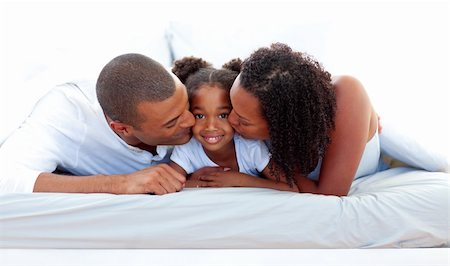Cheerful parents kissing their daughter lying on a bed Stock Photo - Budget Royalty-Free & Subscription, Code: 400-04192369