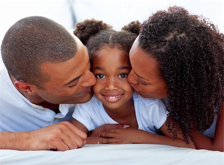 Loving parents kissing their daughter lying on a bed Stock Photo - Budget Royalty-Free & Subscription, Code: 400-04192370