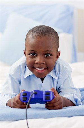 Cute little boy playing video game lying on a bed Stock Photo - Budget Royalty-Free & Subscription, Code: 400-04192469