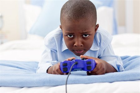 simsearch:400-04199147,k - Happy little boy playing video game lying on a bed Photographie de stock - Aubaine LD & Abonnement, Code: 400-04192470