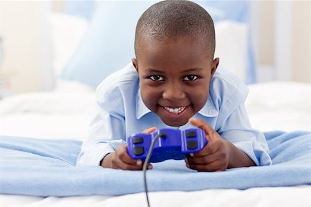 Little boy playing video games and lying on bed Stock Photo - Budget Royalty-Free & Subscription, Code: 400-04192471
