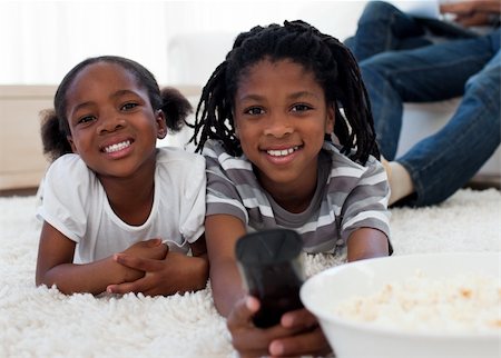 Afro american children watching television and eating pop corn in the living room Stock Photo - Budget Royalty-Free & Subscription, Code: 400-04192527
