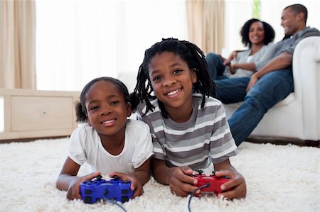 Happy siblings playing video game lying on the floor Stock Photo - Budget Royalty-Free & Subscription, Code: 400-04192538