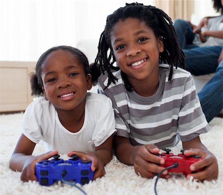 Close-up of siblings playing video game lying on the floor Stock Photo - Budget Royalty-Free & Subscription, Code: 400-04192539