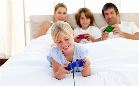 simsearch:400-04199147,k - Cute blond girl playing video game with her family in the bedroom Photographie de stock - Aubaine LD & Abonnement, Code: 400-04193056