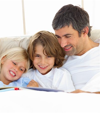 simsearch:400-04192370,k - Close-up of father and his children reading book lying in bed Fotografie stock - Microstock e Abbonamento, Codice: 400-04193070