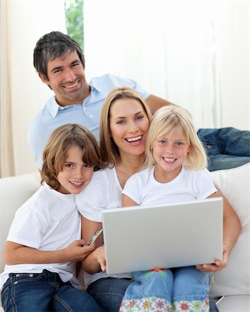 Happy family using a laptop sitting on sofa at home Stock Photo - Budget Royalty-Free & Subscription, Code: 400-04193247
