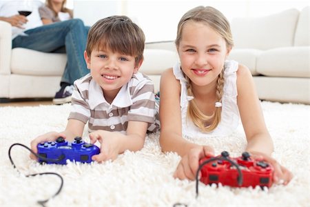 Cute brother and sister playing video games lying on the floor Stock Photo - Budget Royalty-Free & Subscription, Code: 400-04193256