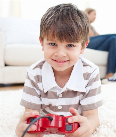 Close-up of little boy playing video games lying on the floor Stock Photo - Budget Royalty-Free & Subscription, Code: 400-04193258