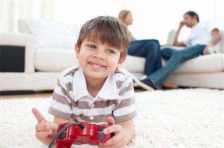 Smiling little boy playing video games lying on the floor Stock Photo - Budget Royalty-Free & Subscription, Code: 400-04193259