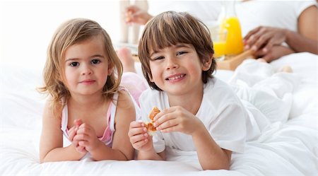 Smiling siblings having breakfast lying on the bed Stock Photo - Budget Royalty-Free & Subscription, Code: 400-04193375