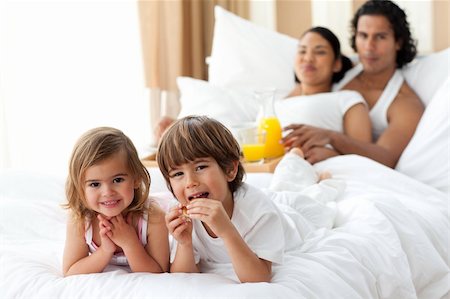 Happy siblings having breakfast with their parents lying on the bed Stock Photo - Budget Royalty-Free & Subscription, Code: 400-04193376