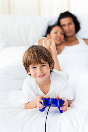 simsearch:400-04157521,k - Liitle boy playing video games with parents in the background Stock Photo - Budget Royalty-Free & Subscription, Code: 400-04193386