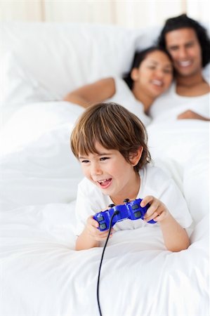 Cute little boy playing video games lying on the bed Stock Photo - Budget Royalty-Free & Subscription, Code: 400-04193387