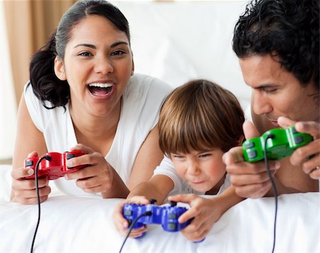 simsearch:400-04157519,k - Happy family playing video games lying on the bed Stock Photo - Budget Royalty-Free & Subscription, Code: 400-04193388