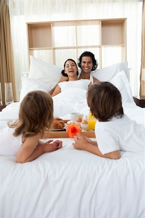 Happy family having breakfast lying on the bed together Foto de stock - Super Valor sin royalties y Suscripción, Código: 400-04193411