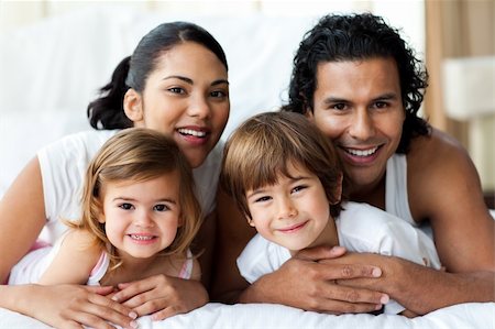 simsearch:400-04192370,k - Happy family smiling at the camera in the bedroom Fotografie stock - Microstock e Abbonamento, Codice: 400-04193432