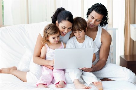 Happy family using a laptop on the bed Stock Photo - Budget Royalty-Free & Subscription, Code: 400-04193444