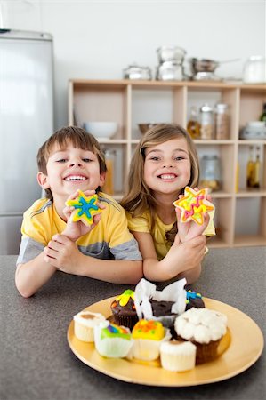 simsearch:695-05773760,k - Frères et soeurs adorables montrant leurs cookies dans la cuisine Photographie de stock - Aubaine LD & Abonnement, Code: 400-04193504
