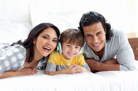 Cute little boy listening to music with his parents on a bed Stock Photo - Budget Royalty-Free & Subscription, Code: 400-04193501