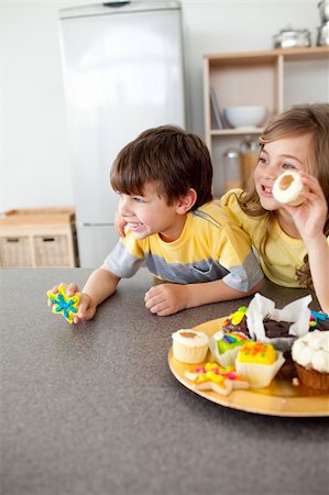 simsearch:695-05773760,k - Smiling children showing their cookies in the kitchen Photographie de stock - Aubaine LD & Abonnement, Code: 400-04193512