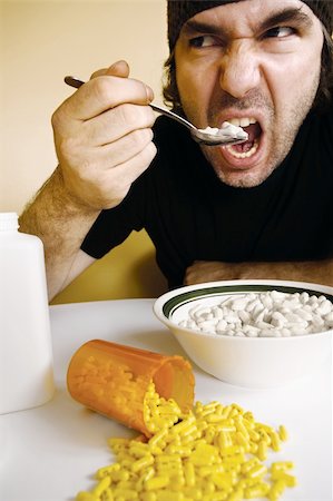 A man feeding himself medication with a spoon. Metaphor for addiction, dependency, etc. Stock Photo - Budget Royalty-Free & Subscription, Code: 400-04193696
