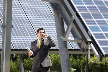 Portrait of mid adult italian male engineer holding blueprints in solar power station and talking on mobile phone. Horizontal shape, front view. Copy space Stock Photo - Budget Royalty-Free & Subscription, Code: 400-04193855