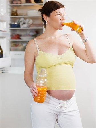 italian 6 months pregnant woman standing near refrigerator and drinking orange juice. Three quarter length, vertical shape Stock Photo - Budget Royalty-Free & Subscription, Code: 400-04204147