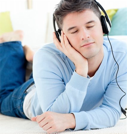 simsearch:400-04207132,k - Relaxed man lying on the floor listening to music with headphones closed eyes in the living room Foto de stock - Super Valor sin royalties y Suscripción, Código: 400-04204844