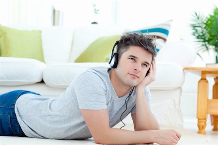 simsearch:400-04207132,k - Young man with headphones lying on the floor in the living room listening to music Foto de stock - Super Valor sin royalties y Suscripción, Código: 400-04204847