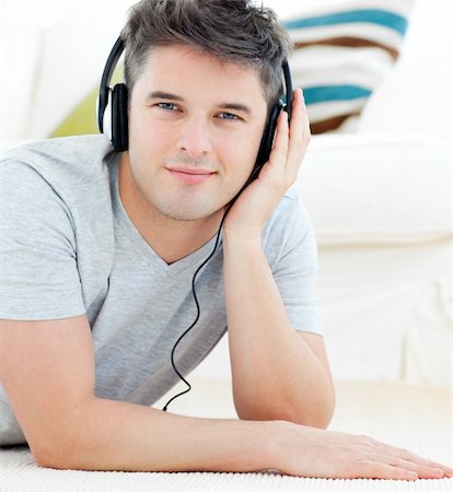 simsearch:400-04207132,k - Portrait of a happy man with headphones looking at the camera lying on the floor in the living room Foto de stock - Super Valor sin royalties y Suscripción, Código: 400-04204848