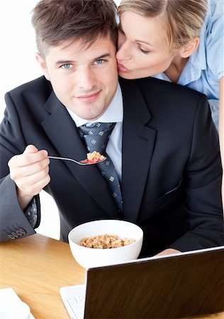 simsearch:400-05209351,k - Smiling businessman eating breakfast using laptop while wife kissing his cheek Stock Photo - Budget Royalty-Free & Subscription, Code: 400-04204892