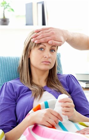 simsearch:400-04212905,k - Depressed woman lying on a sofa man feel her temperature in the living room Stock Photo - Budget Royalty-Free & Subscription, Code: 400-04204907