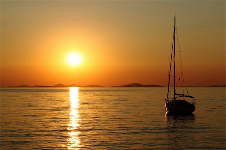 simsearch:400-06101259,k - Gold romantic sunset with silhouette of yacht Fotografie stock - Microstock e Abbonamento, Codice: 400-04206332
