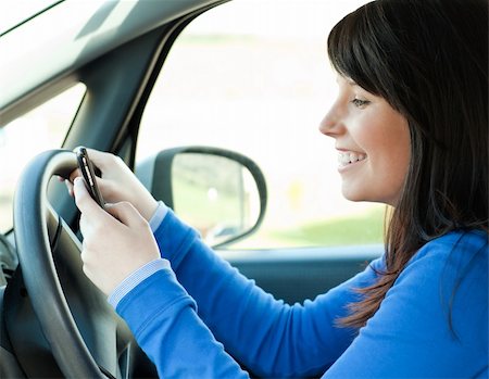 simsearch:400-04843851,k - Brunette young woman sending a message with her mobile phone sitting in her car Stockbilder - Microstock & Abonnement, Bildnummer: 400-04206755