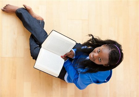 simsearch:400-05716909,k - Delighted young woman looking up at the camera holidng a book sitting on the floor Stock Photo - Budget Royalty-Free & Subscription, Code: 400-04206770