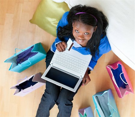 simsearch:400-04709946,k - Cheerful afro-american teenager using a laptop sitting between shopping bags on the floor in the living room Stockbilder - Microstock & Abonnement, Bildnummer: 400-04206773