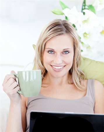 simsearch:400-05749531,k - Woman sitting in front of her laptop and holding a cup in the living room Stock Photo - Budget Royalty-Free & Subscription, Code: 400-04207985