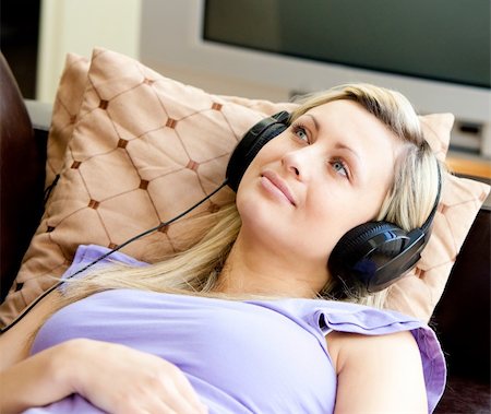 simsearch:400-04905827,k - Happy woman listen to music wearing headphones lying on a sofa Stock Photo - Budget Royalty-Free & Subscription, Code: 400-04208042