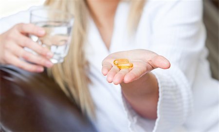 simsearch:400-04201129,k - Cute woman holding pills and a glass of water smiling at the camera sitting on the sofa Stock Photo - Budget Royalty-Free & Subscription, Code: 400-04208052